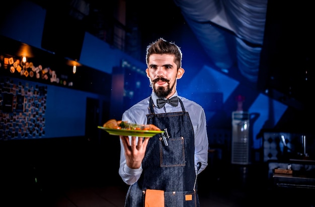 Garcon élégant tient une assiette avec un plat préparé lors d'un événement festif.