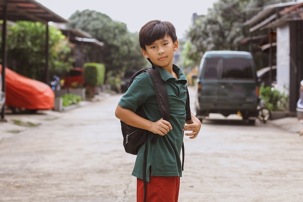 Garçon élémentaire asiatique posant à la caméra avant d'aller à l'école