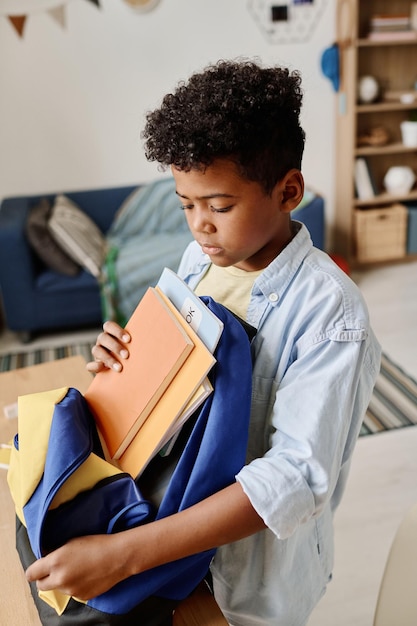 Garçon emballant des livres dans son sac d'école