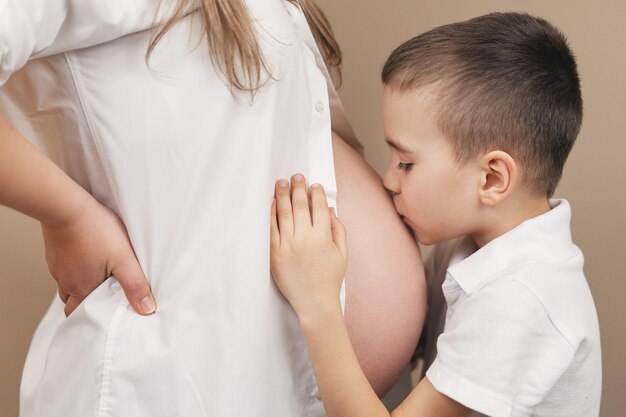 Le garçon embrasse le ventre enceinte de maman