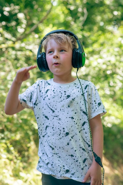 Garçon émotionnel de 9 ans dans la forêt avec des écouteurs écoutant de la musique