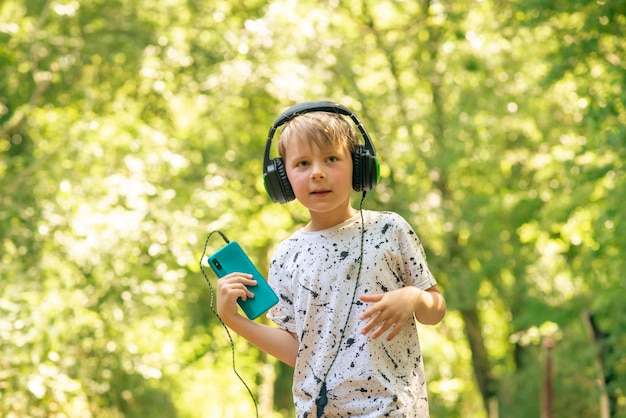 Garçon émotionnel de 9 ans dans la forêt avec des écouteurs écoutant de la musique