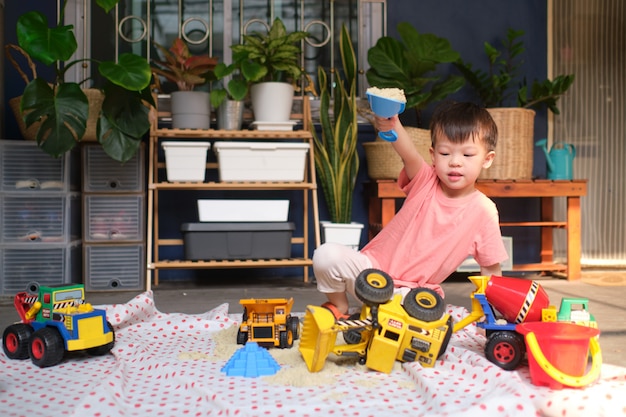 Garçon enfant asiatique jouant avec du sable cinétique à la maison, enfant jouant avec des machines de construction de jouets, éducation Montessori, jeu créatif pour les enfants concept