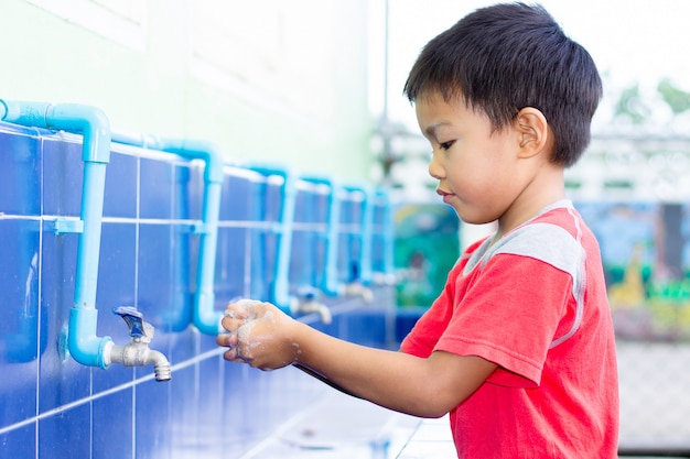 Garçon enfant asiatique se laver les mains avant de manger de la nourriture.