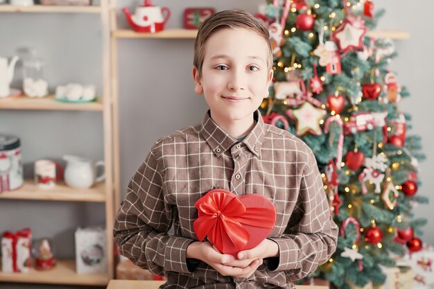 Garçon enfant avec boîte-cadeau et arbre de Noël.