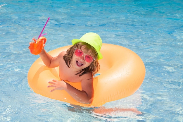 Garçon enfant dans la piscine en train de boire un cocktail de vie heureux pour les enfants de l'eau jouet activité de plein air saine pour les enfants