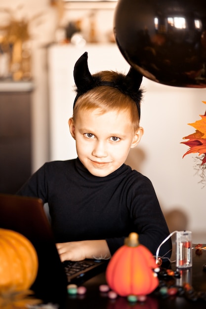 Garçon enfant drôle en costume maléfique pour Halloween à l'aide d'un ordinateur portable tablette numérique. Appelez en ligne des amis ou des parents.