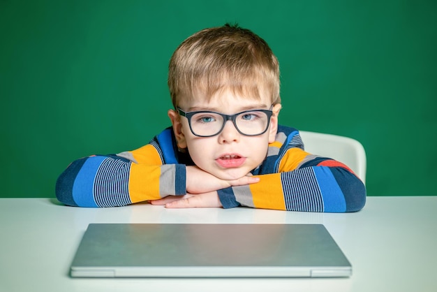 Garçon enfant est assis à la table mettre sa tête dans ses bras dans le studio Gros plan