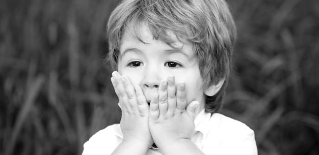 Garçon enfant étonné ou surpris souriant Enfant exprimant sa surprise avec ses mains dans son visage Garçon choqué et surpris Enfant garçon drôle