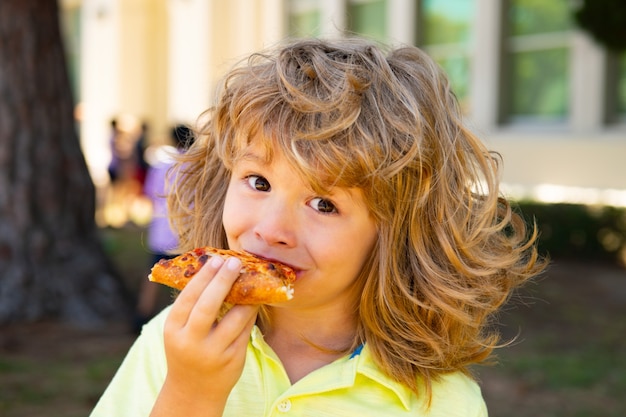 Garçon enfant mangeant un morceau de pizza. L'enfant mange une tranche de pizza au pepperoni. Les enfants adorent les pizzas.