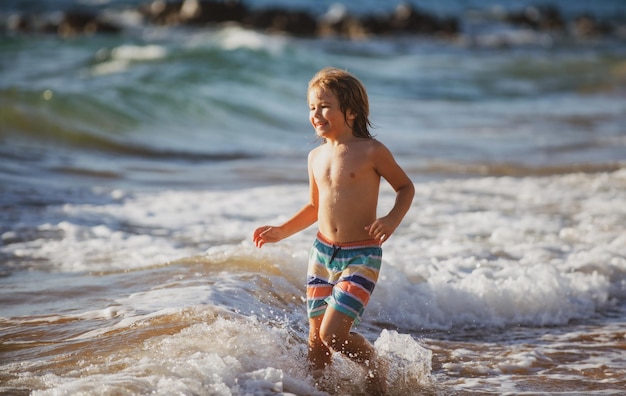 Garçon enfant sautant dans les vagues de la mer sauter par l'eau la mer éclabousse les vacances d'été des enfants