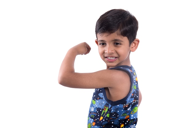 Garçon enfant souriant montrant sa force de muscles biceps main sur fond blanc.