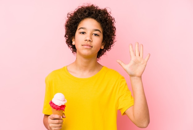 Garçon enfant tenant une glace isolée souriant joyeux montrant le numéro cinq avec les doigts.