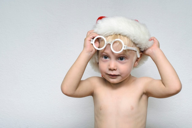 Garçon enlève ses lunettes et son chapeau de père Noël