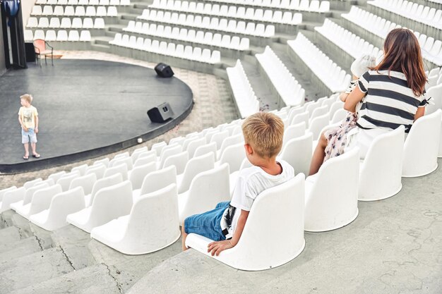 Un garçon essaie de chanter pour ses frères et sa mère dans un amphithéâtre vide