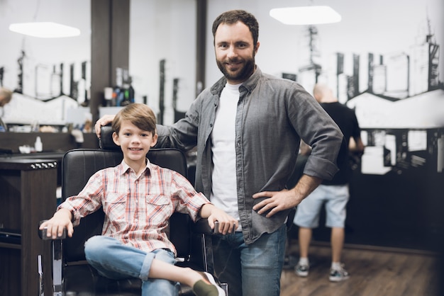 Le garçon est assis dans le salon de coiffure du coiffeur
