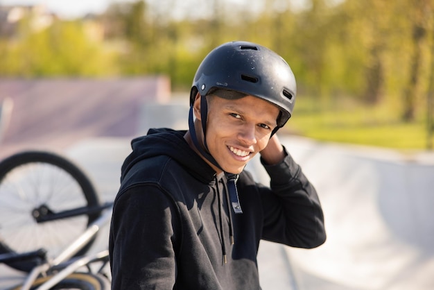 Un garçon est assis sur une rampe dans un skatepark avec son vélo couché derrière lui