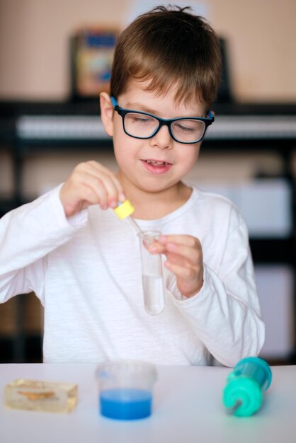 Le garçon est engagé dans la recherche scientifique Un enfant avec un tube à essai et une pipette dans ses mains Le garçon fait une expérience à la maison