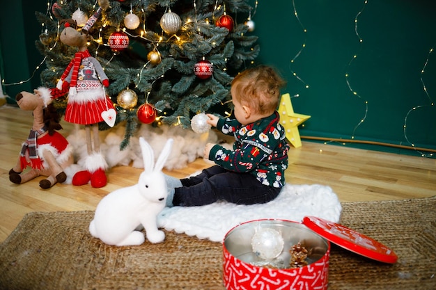 Un garçon est à la maison près de l'arbre de Noël à la recherche de cadeaux du Nouvel An du Père Noël