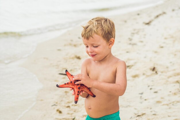 Un garçon et une étoile de mer rouge sur fond de mer