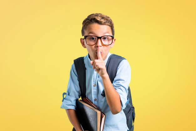 Garçon étudiant avec sac à dos et lunettes montrant un signe de fermeture de la bouche