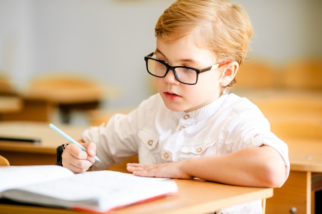 Garçon étudiant à la table sur fond de classe