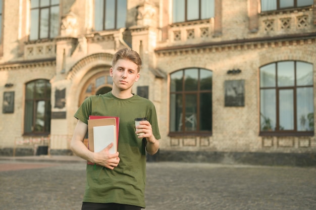 Garçon étudiant universitaire positif souriant près du campus avec des livres