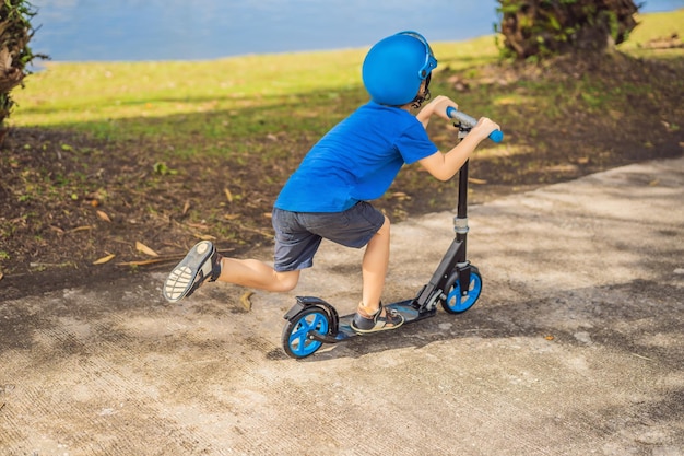 Garçon faisant du scooter en plein air dans le parc l'été Les enfants sont heureux de jouer à l'extérieur