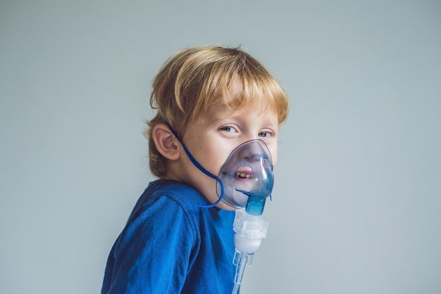 Garçon faisant l'inhalation avec un nébuliseur à la maison.