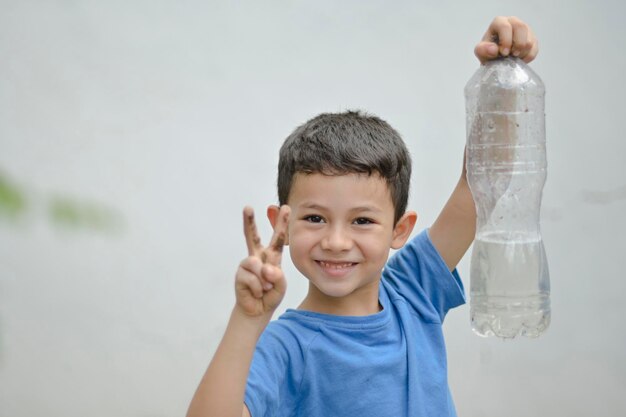 Garçon faisant un signe de paix avec ses mains garçon tenant une bouteille d'eau recyclée