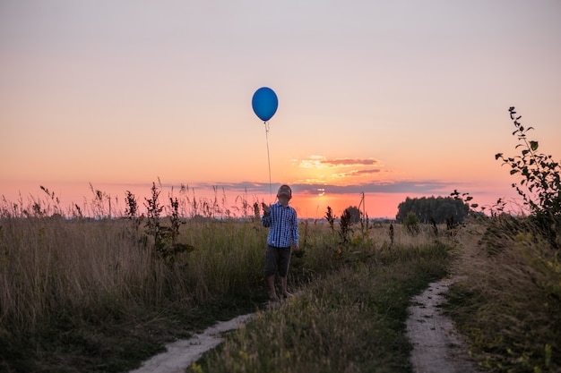 Garçon fait ses rêves à l'extérieur avec Balloon Run le long du terrain Belle liberté de carte d'été