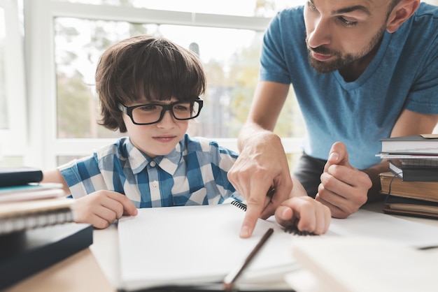 Un garçon fatigué des devoirs de papa l'aide.