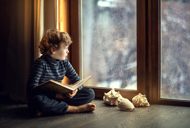 garçon à la fenêtre lisant un livre