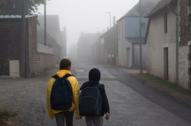 Un garçon et une fille de 8 ans avec un sac à dos vont à l'école le long d'une route de campagne le matin seuls au printemps