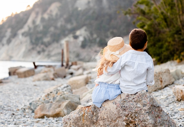 Garçon et fille assise sur une pierre sur la plage