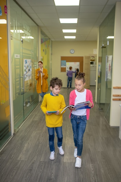 Garçon et fille debout dans le couloir avec des manuels dans leurs mains