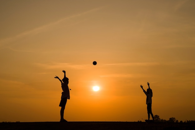 garçon et fille jouant au ballon au coucher du soleil