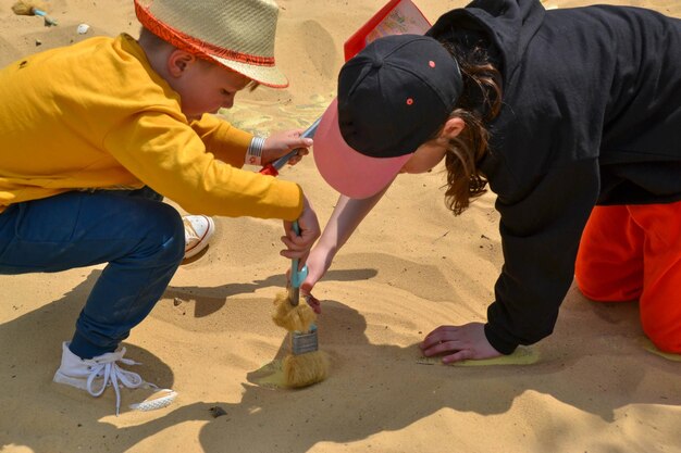 Photo un garçon et une fille jouent dans le sable avec un balai.