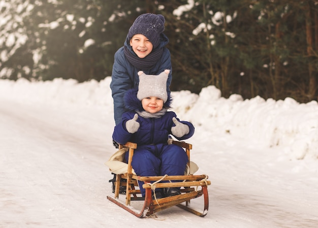 Un garçon et une fille luge en hiver dans la nature. Frère et soeur ensemble