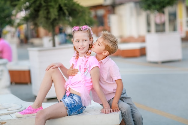 Garçon et fille parents assis dans le parc sur un banc blanc