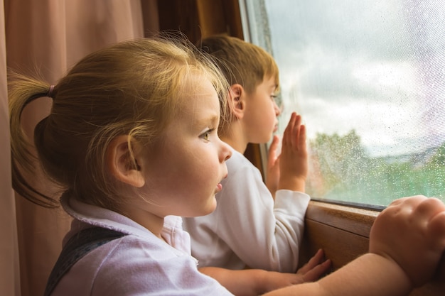 Le garçon et la fille regardent dans une fenêtre