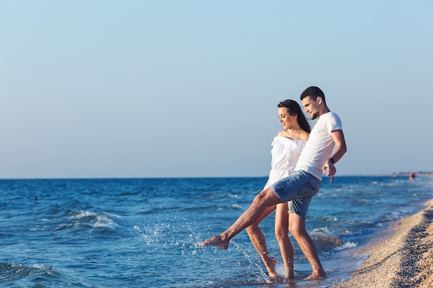 Garçon et fille s'amusent à s'éclabousser sur la mer.