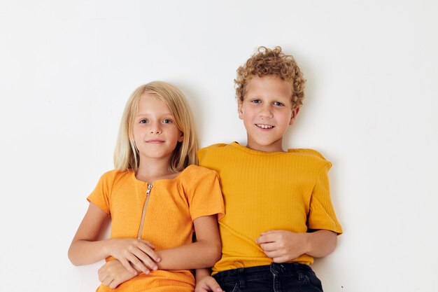 Garçon et fille se trouvent sur un fond blanc dans des émotions de t-shirts jaunes