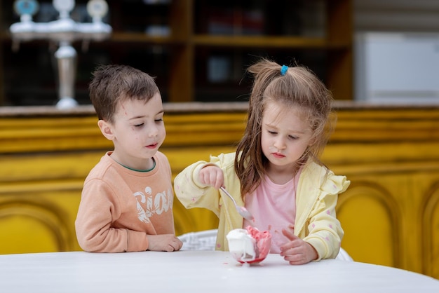 Photo un garçon et une fille sont assis à une table avec de la glace.