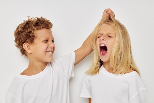 Garçon et fille en t-shirts blancs se tiennent à côté d'un fond isolé