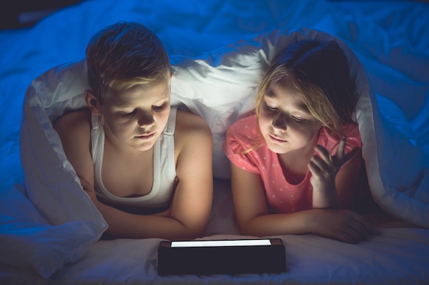 Le garçon et la fille avec une tablette et une lampe de poche étaient à couvert. La nuit