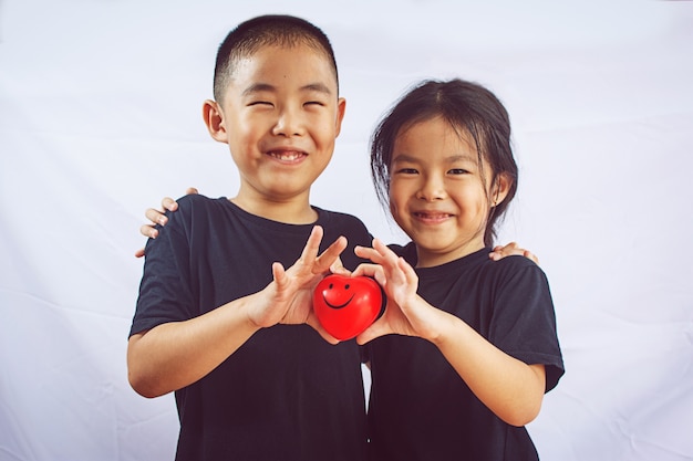 Garçon et fille tiennent coeur rouge