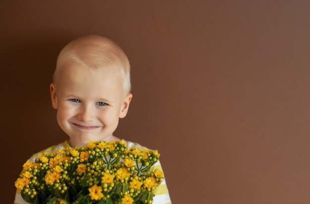 Garçon avec des fleurs. enfant souriant avec un bouquet de fleurs.