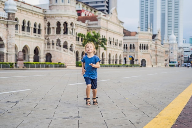 Garçon sur fond de bâtiment Sultan Abdul Samad à Kuala Lumpur, Malaisie. Voyager avec le concept d'enfants