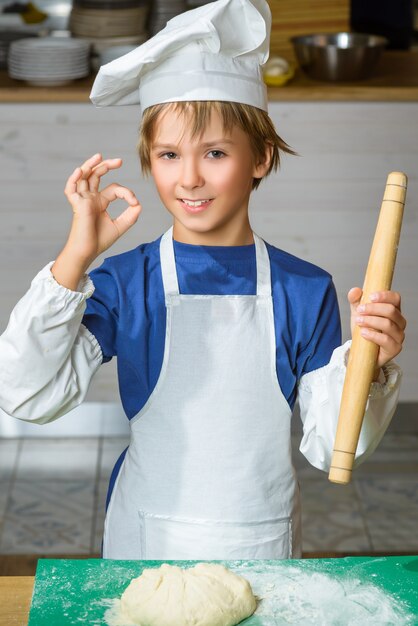 Garçon habillé en cuisinier prépare la pâte